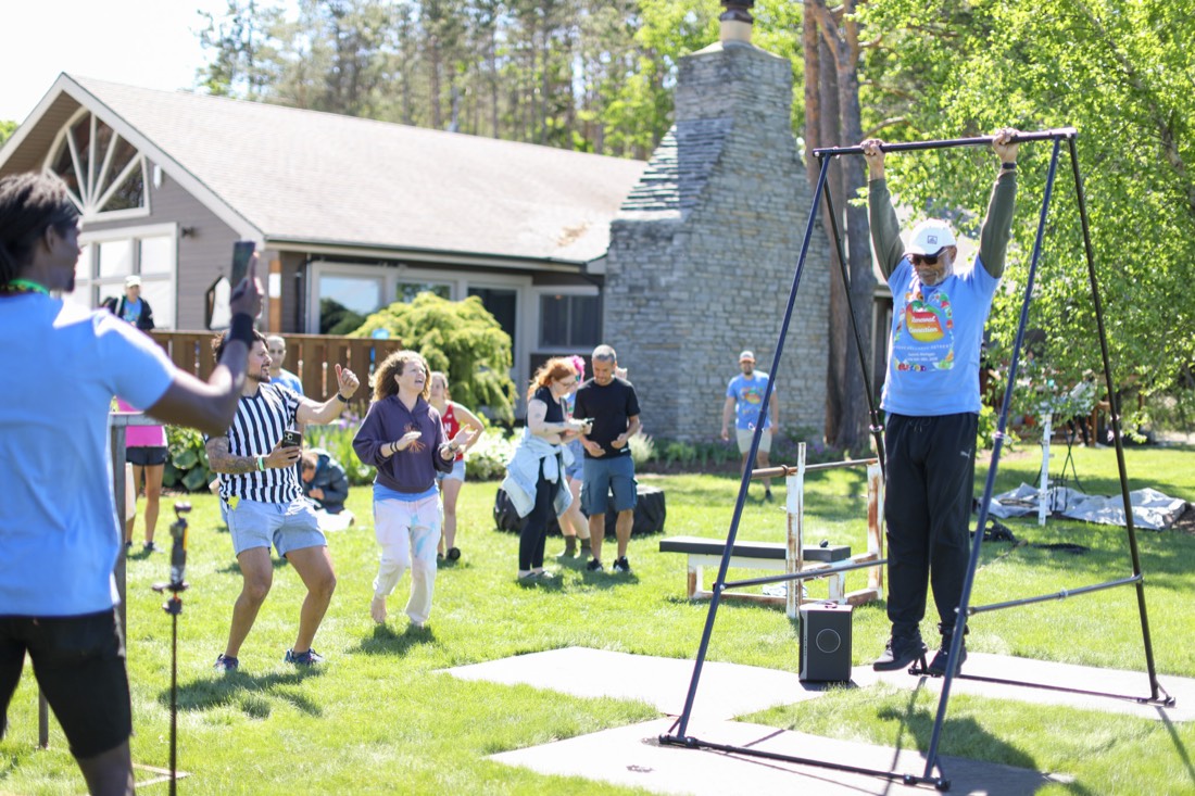 Older competitor powering through a pull-up as the crowd cheers at the 2026 Vegan Olympics