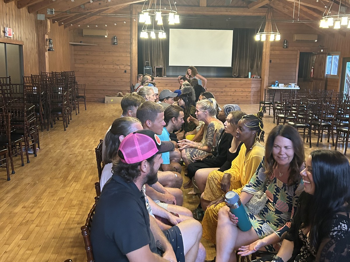 Two long rows of guests seated facing each other, talking and laughing, during Speed Dating night in the great hall at a Vegan Wellness Retreat